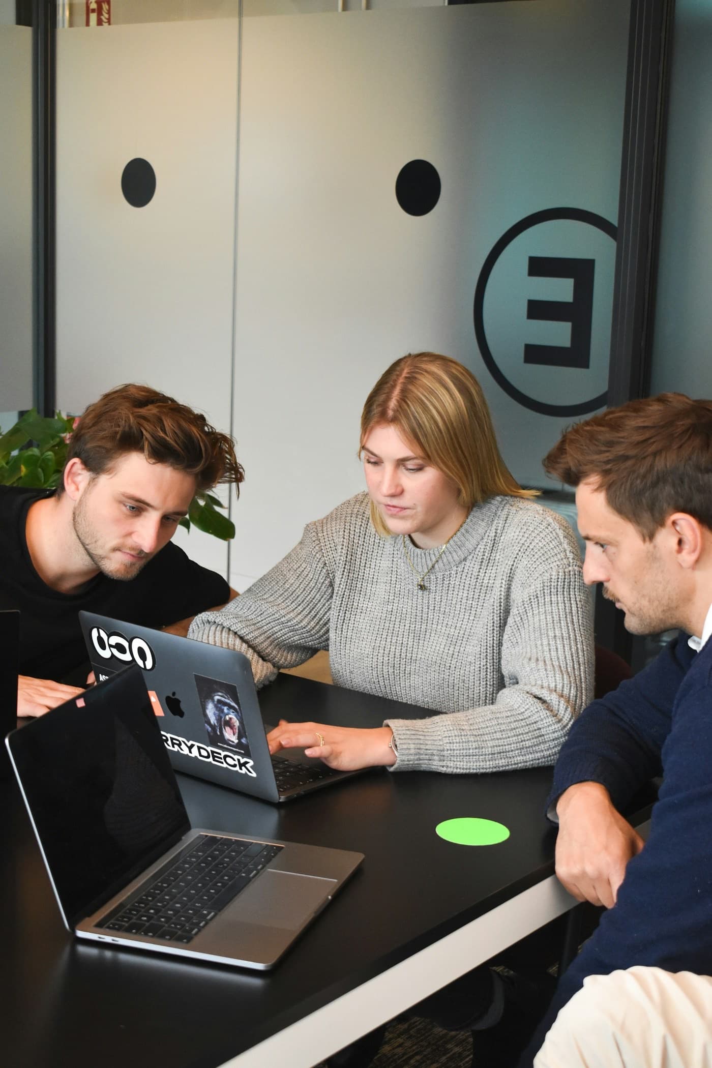 Drei Personen besprechen gemeinsam etwas an einem Laptop